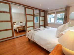 a bedroom with a large white bed and a mirror at Cramar Cottage in Glasgow