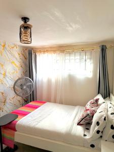 Un dormitorio con una cama y una ventana con ventilador. en The Hideout-Studio Apartment in Westlands, en Nairobi 1 foto más