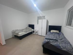 阿什杜德Luxury 5 Rooms Apartments 3 minutes from beach的一间卧室设有两张床和白色的墙壁 更多8张照片