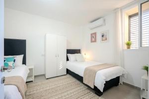 阿什杜德Luxury 5 Rooms Apartments 3 minutes from beach的一间带两张床和一扇窗户的白色卧室