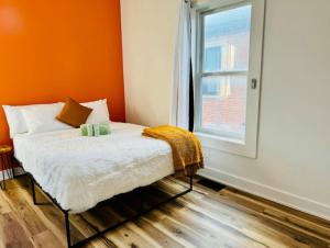 a bedroom with a bed with an orange wall and a window at Jungle House Luxury Homes - Columbus Downtown Short North - Steps to Convention Center & Nationwide Arena - Sleeps up to 8 - Free Parking - Over 5,800 Five Stars in Columbus