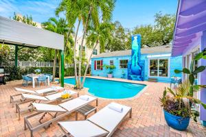 ein Pool mit Liegestühlen und ein blaues Haus in der Unterkunft Heated Pool Las Olas Victoria Park Near Beach Escapism at its finest Mermaid Key in Fort Lauderdale