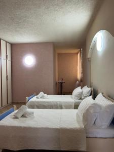 una camera d'albergo con tre letti con lenzuola bianche di Hana's Apartment a Durrës