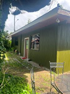 ein grünes Haus mit einem Tisch davor in der Unterkunft Casa Alma in Pucón