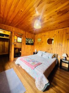 ein Schlafzimmer mit einem Bett in einer Holzhütte in der Unterkunft Casa Alma in Pucón