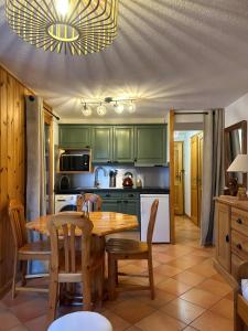 a kitchen with green cabinets and a wooden table and chairs at Samoëns à Pied – Appt 4 pers in Samoëns