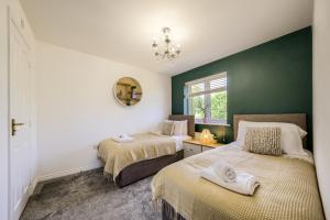 a bedroom with two beds and a green wall at NEW! Private Driveway, Spacious, 2 Bathroom, Fast WiFi in Berkswell
