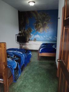 ein Schlafzimmer mit 2 Betten und einem Wandgemälde in der Unterkunft Cabinas Dormi Bene in Miramar