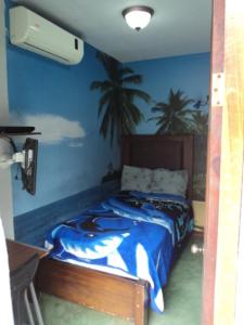 a bedroom with a bed with palm trees on the wall at Cabinas Dormi Bene in Miramar