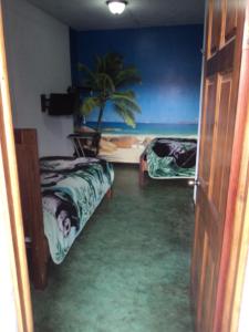 a room with two beds and a palm tree in it at Cabinas Dormi Bene in Miramar