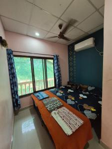 een slaapkamer met een bed en een groot raam bij anandi holidays homestay in Malvan