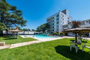 a pool with chairs and umbrellas next to a building at Gran Hotel Las Lajas in Villa Carlos Paz +30 photos