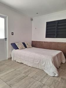 a bed in a white room with a bed sidx sidx sidx at Departamento Temporal en Villa Carlos Paz in Villa Carlos Paz