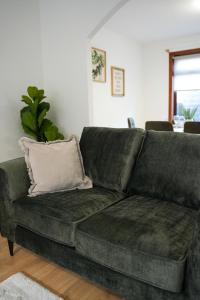 un divano verde in un soggiorno con un cuscino di Nigel House a Livingston