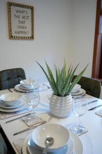 un tavolo con piatti e bicchieri e una pianta in vaso di Nigel House a Livingston Altre 26 foto