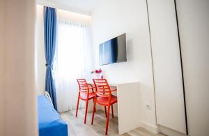 Habitación con mesa con sillas rojas y TV. en Studio Pop Art, en Batajnica