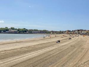a sandy beach with people on it next to the water at Betty's Buoy in Weymouth +20 photos