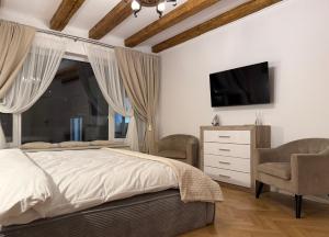 Un dormitorio con una cama, un televisor y una silla. en The Bucket - Calla Old Town with Jacuzzi, en Brasov