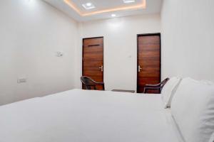 a bedroom with two doors and a bed and two chairs at Hotel O The Kavish in Somarda Kauasot +29 photos