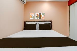 a bedroom with a bed and two paintings on the wall at Hotel O Prasad Inn in Ballygunge