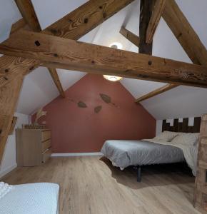 1 dormitorio en el ático con cama y vigas de madera en Jo And Manu's Barn, en Falaise