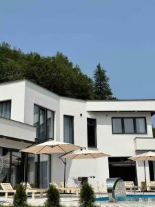 a white building with umbrellas next to a swimming pool at Vila Amore Sarajevo Bjelasnica 