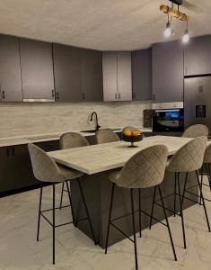 a kitchen with a large island with chairs around it at Vila Amore Sarajevo Bjelasnica 