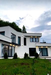 a white house with black windows and a green field at Vila Amore Sarajevo Bjelasnica 