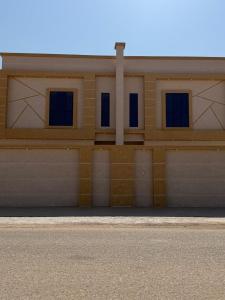ein Gebäude mit zwei Garagentoren und drei Fenstern in der Unterkunft فلة الشروق - Sunrise Villa in Sur
