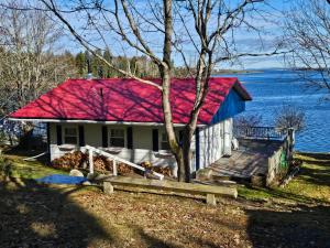 a house with a red roof on the shore of a lake at Islandview Cottage in Lunenburg
