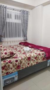 a bedroom with a bed with flowers on it at Properti9 at Apartemen Green Pramuka in Jakarta