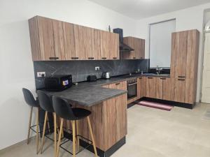 a kitchen with wooden cabinets and a counter with bar stools at Maisonette Gzira in Il-Gżira