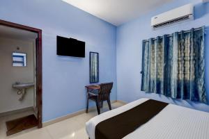 钦奈Hotel O Dream inn的一间卧室，里面有一张床、一张桌子和一台电视。