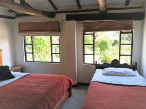 two beds in a room with two windows at Finca La Mara in Tibasosa