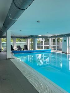 a large pool with blue water in a building at Fresh Garden Casa Mimo in Siófok