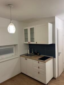 a kitchen with white cabinets and a sink at Fresh Garden Casa Mimo in Siófok