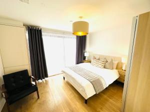 een slaapkamer met een bed, een stoel en een raam bij Westferry Deluxe Apartment 3 in Londen