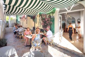 Un grupo de personas sentadas en mesas en un patio. en Bella Vista Beach Hotel, en Benitses