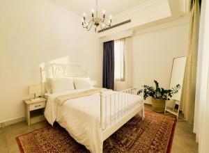 a white bedroom with a white bed and a chandelier at Mid-Century Modern Comfort 1BR in Abu Dhabi