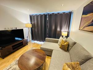 een woonkamer met een bank, een tafel en een televisie bij Westferry Deluxe Apartment 3 in Londen