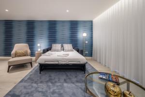 a bedroom with a bed and a chair and a glass table at Land Roots Riverside Apartments in Vila Nova de Gaia +60 photos