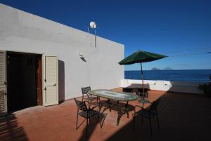 a patio with a table and chairs and an umbrella at Oasi 2 terrace overlooking the sea in Canneto in Canneto - Lipari
