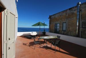 a patio with a table and chairs and an umbrella at Oasi 2 terrace overlooking the sea in Canneto in Canneto - Lipari