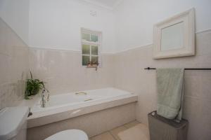 a bathroom with a tub and a toilet and a sink at Sunny Poolside Escape in Somerset West in Somerset West +7 photos