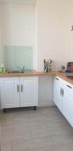 Centre ville Angouleme في أنغوليم: مطبخ بخزائن بيضاء وطاولة خشبية +4 صور