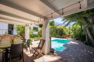 a patio with a table and chairs and a swimming pool at Sunny Poolside Escape in Somerset West in Somerset West