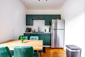 a kitchen with green cabinets and a table and a refrigerator at Jungle House Chillicothe Sleeps 24 Downtown Ohio Free Parking - Walk to Historic District - 5BR Luxury Home - Pet Friendly - King Beds - Over 5,800 Five Star Stays in Chillicothe +153 photos