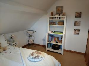 a bedroom with a bed and a book shelf at Carnowen Cottage in Ringsend