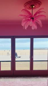 a pink room with a view of the beach at The Rozette Experience in Ostend
