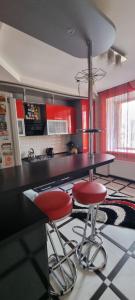 una cucina con mobili rossi e due sgabelli da bar rossi di Квартира в центре города со всеми удобствами a Chmel'nyc'kyj